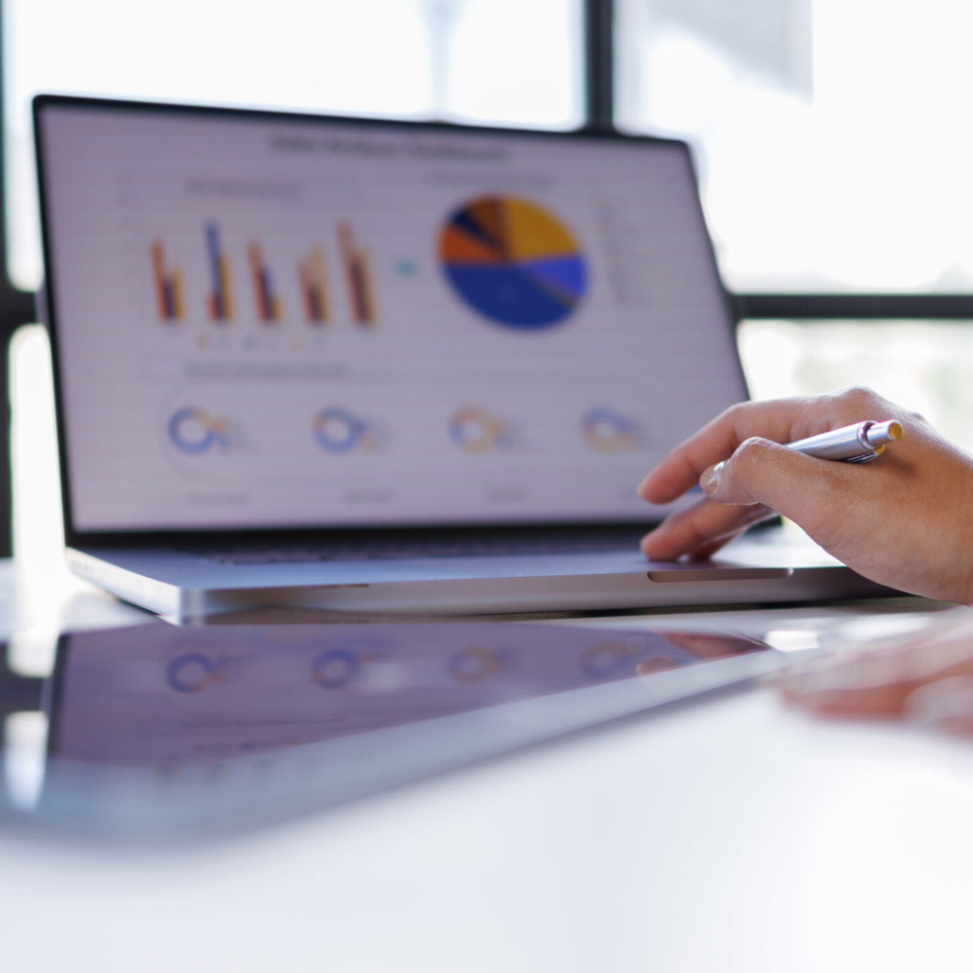 Person using a laptop displaying financial charts and graphs while analysing data.