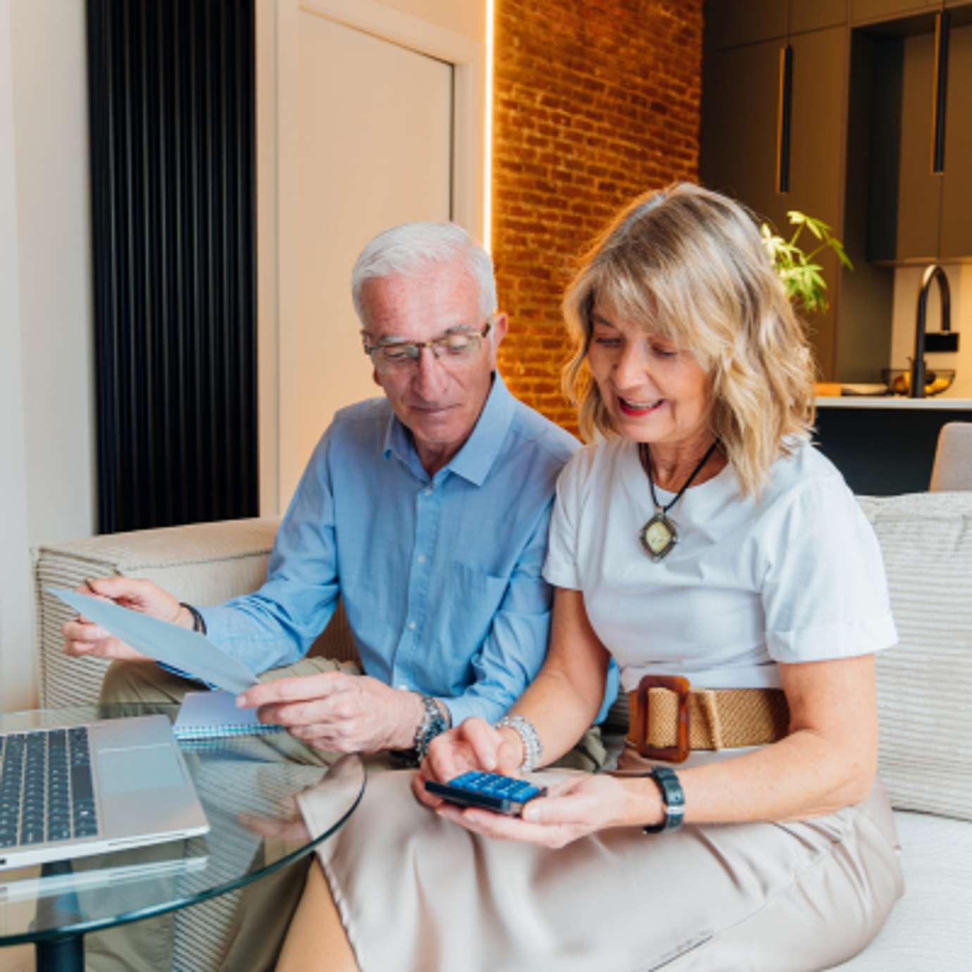 Smiling senior couple sitting together at home reviewing paperwork
