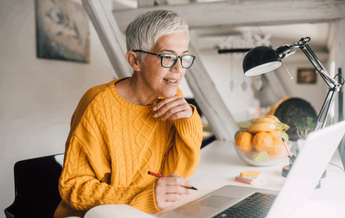 A senior woman sat at her desk looking at her laptop