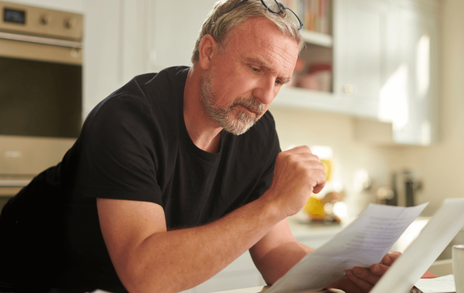 A man reading over forms in his kitchen