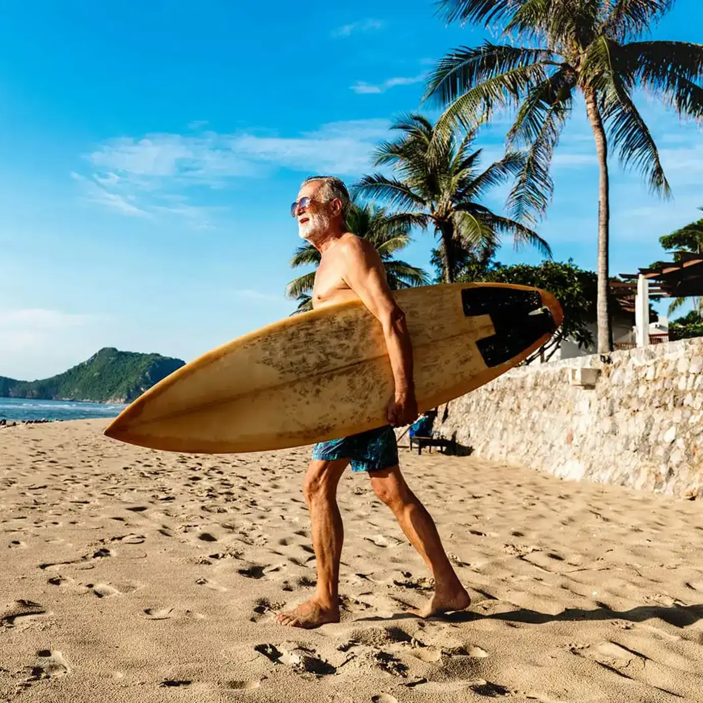 Man with surfboard walking on a beach towards the sea