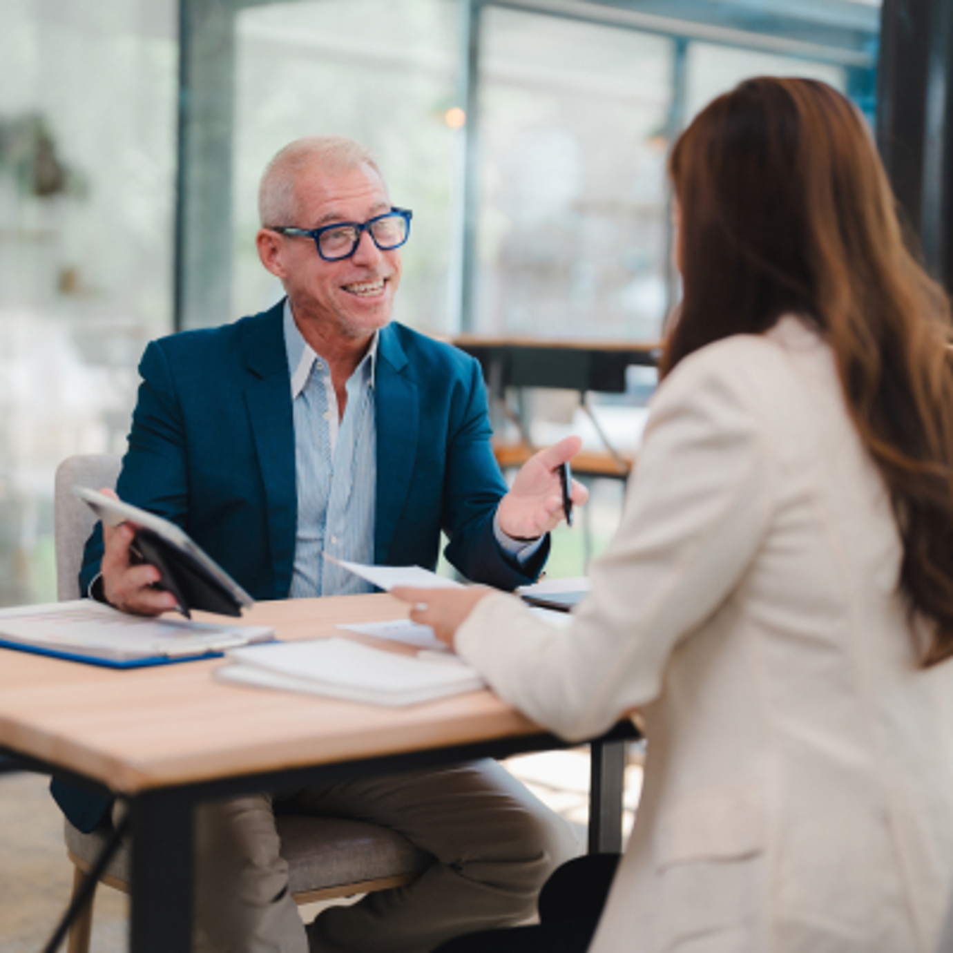 Senior man wearing glasses discussing documents with a female professional during a meeting