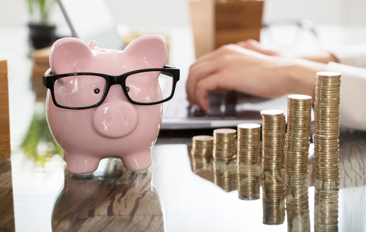 A piggy bank wearing glasses beside six stacks of coins that gradually increase