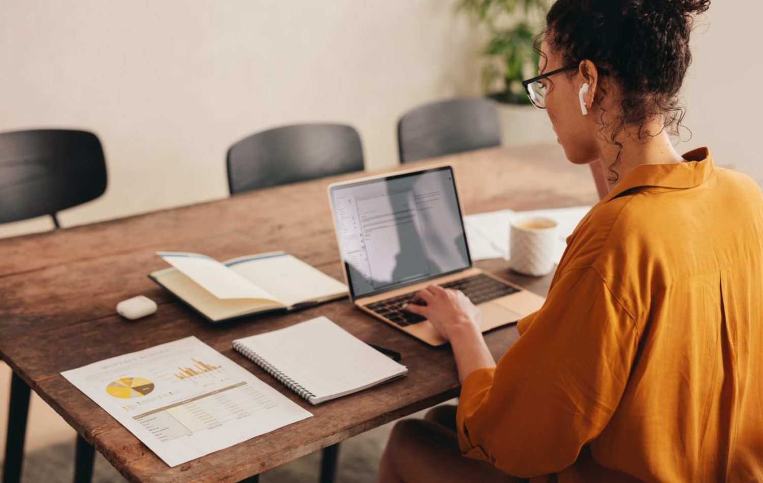 A woman sat at a table with her laptop and forms