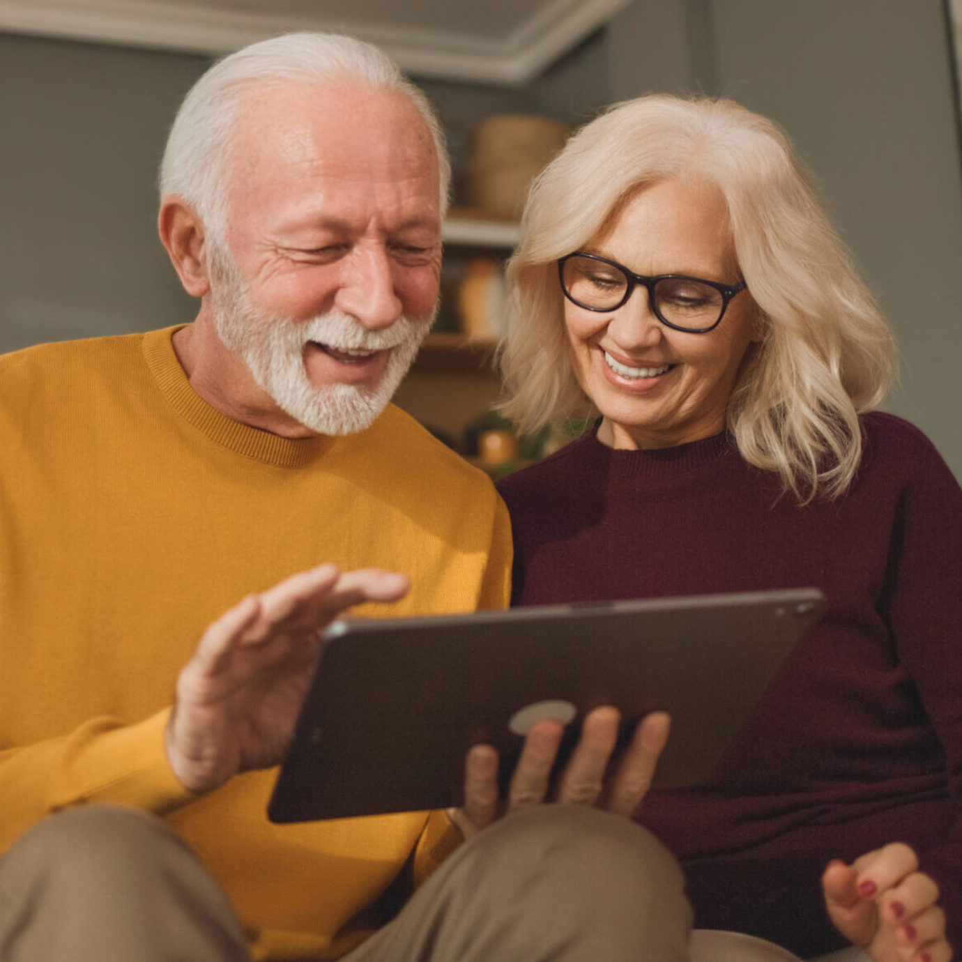 A senior couple looking at a digital tablet screen together, smiling